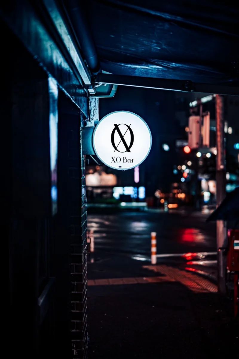 XO BAR 恵比寿 店看板 - 夜の恵比寿の路地で光る丸い看板